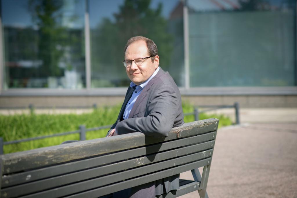 Sami Lundgren on UPM:n vastuullisuusjohtaja. Hän istuu penkillä kauniissa kesäsässä.