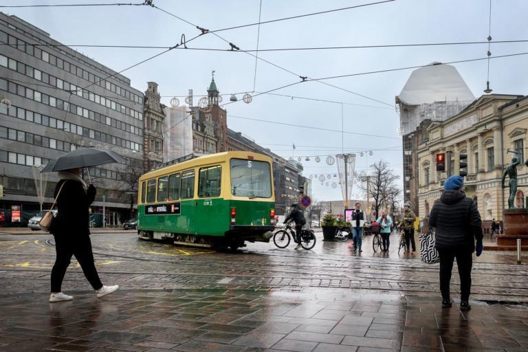Helsingin keskustassa ihmisiä, pyöräilijöitä ja ratikka.
