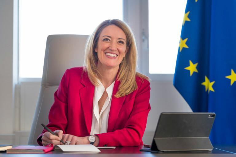 EU-parlamentin puhemies, Roberta Metsola, istuu työpöydän ääressä ja EU-lippu näkyy vasemmalla puolella. Lähde: EP